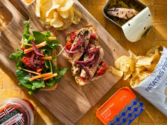 Open mackerel sandwiches on a board with crisps and salad