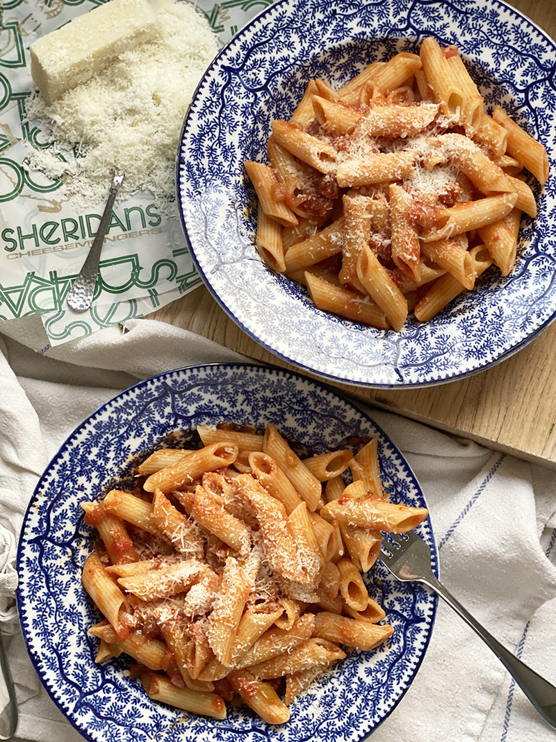 Two blue and white plates of penne with amatriciana sauce