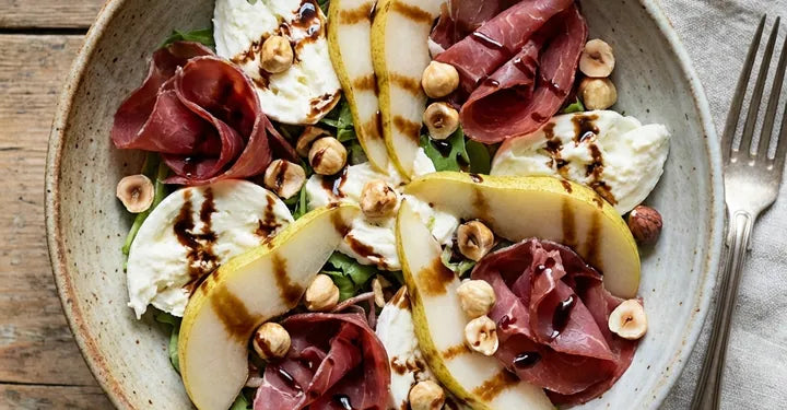 Salad of mozzarella, poached pears, bresaola and hazelnuts on a plate