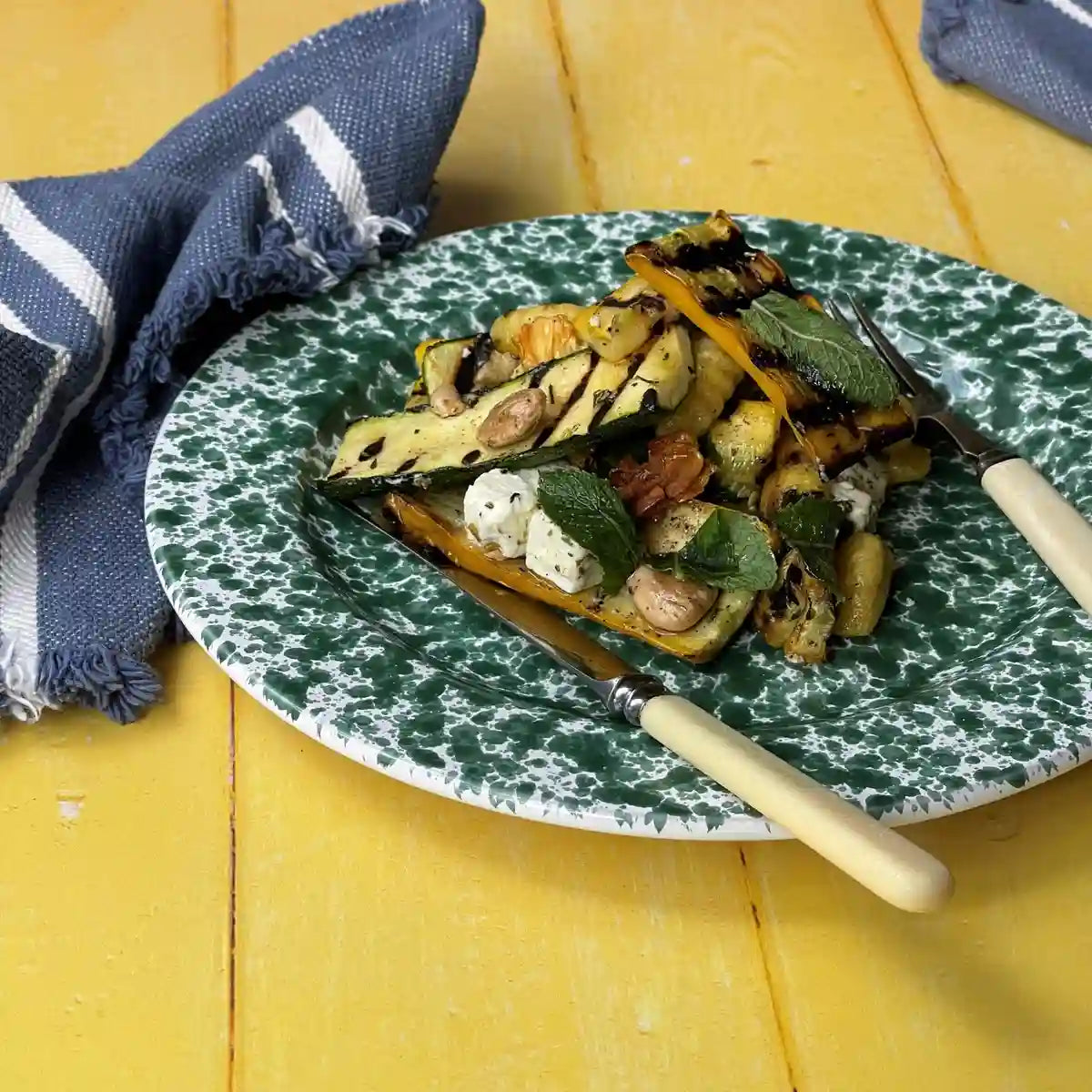 Roasting dish of courgettes and herbs served on a green plate