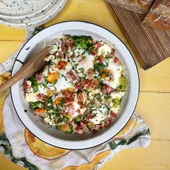 Baked eggs with broccoli and chorizo in a bowl on a yellow cloth