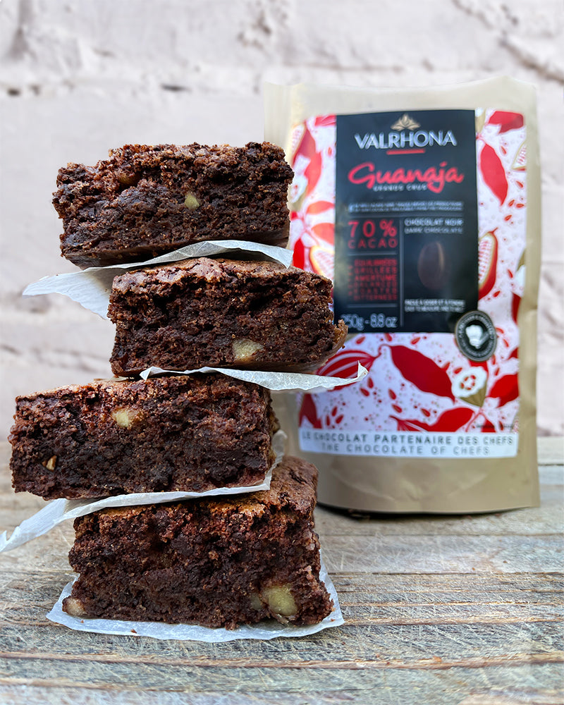Stack of chocolate brownies beside a bag of Valrhona chocolate