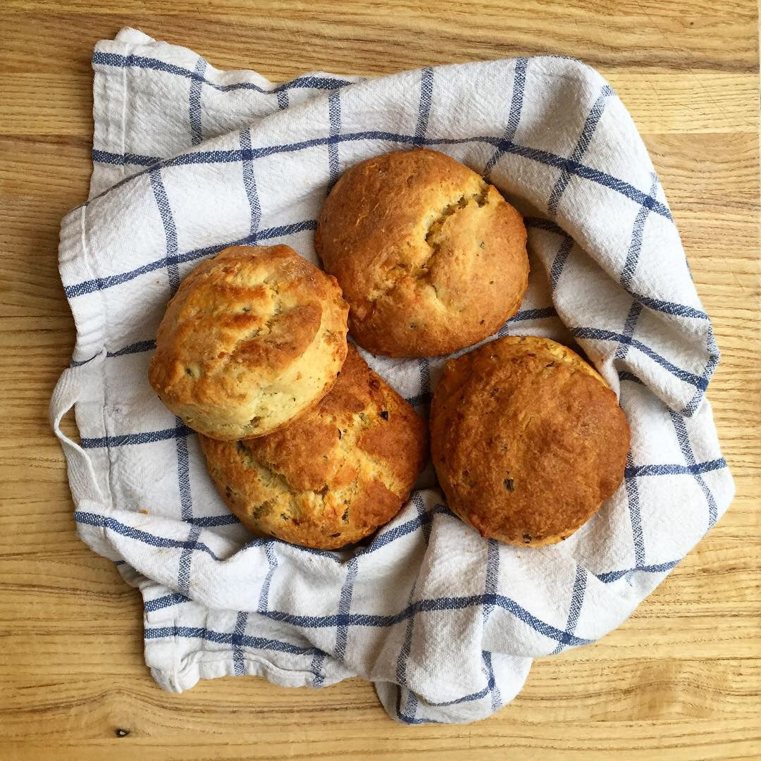 Freshly baked cheddar biscuits on a checked tea towel