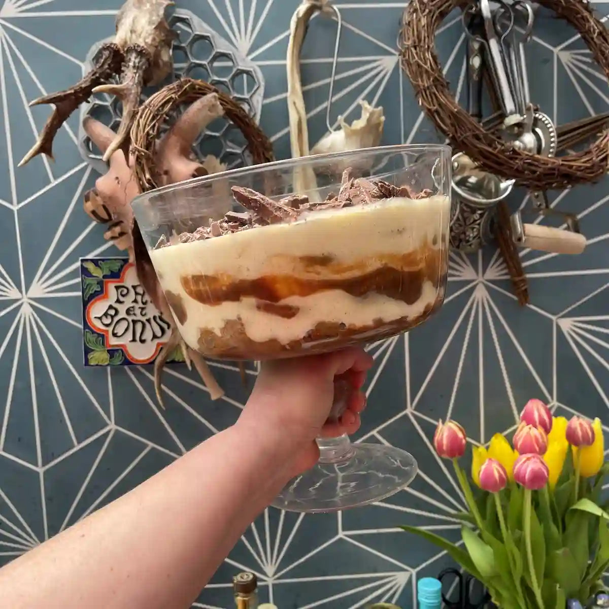Hand holding a glass dish of dulce de leche tiramisu