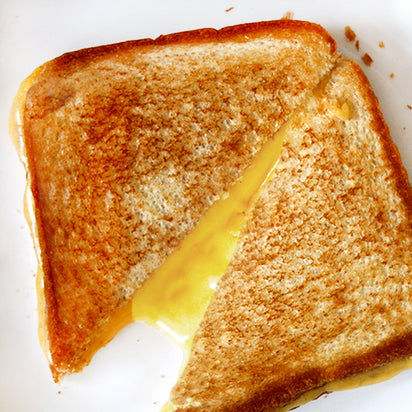 Toasted cheese and ham sandwich cut open with cheese stretching