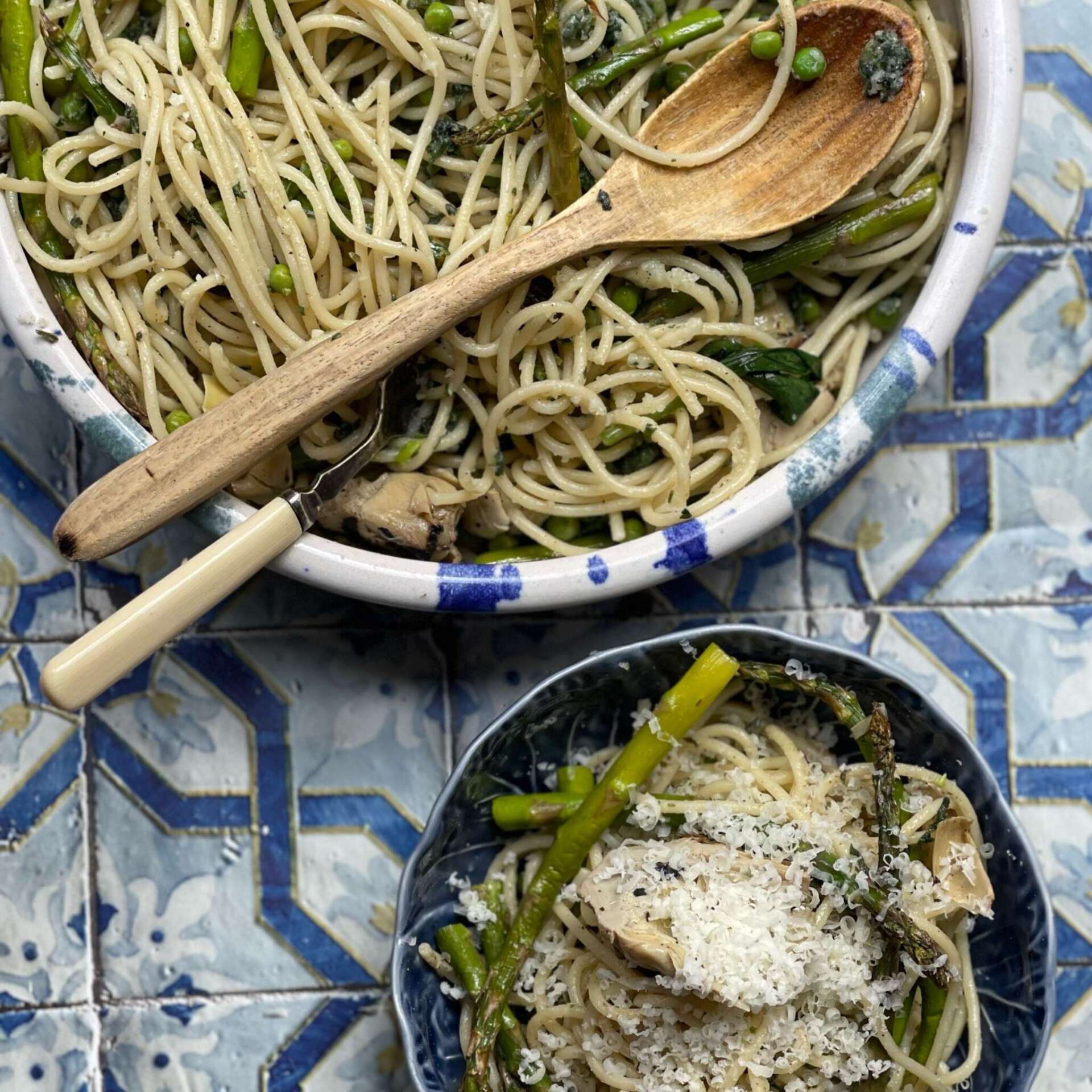 Bowl of sheep gouda cacio e pepe with asparagus on a blue tiled surface