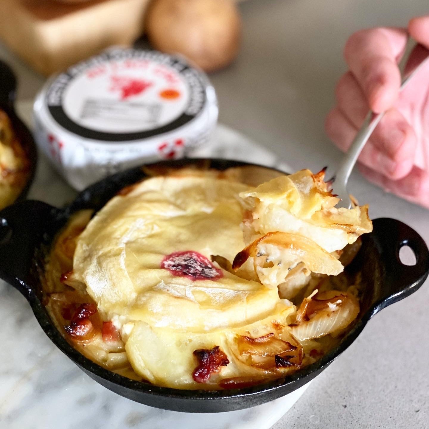 Tartiflette in a cast iron pan topped with melted Reblochon