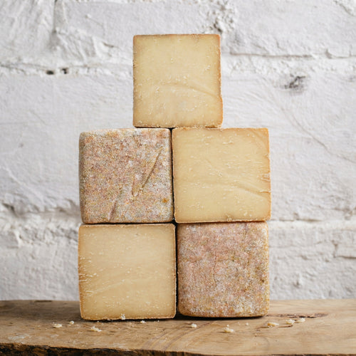 Five square pieces of cheese stacked on a wooden surface with a white textured background