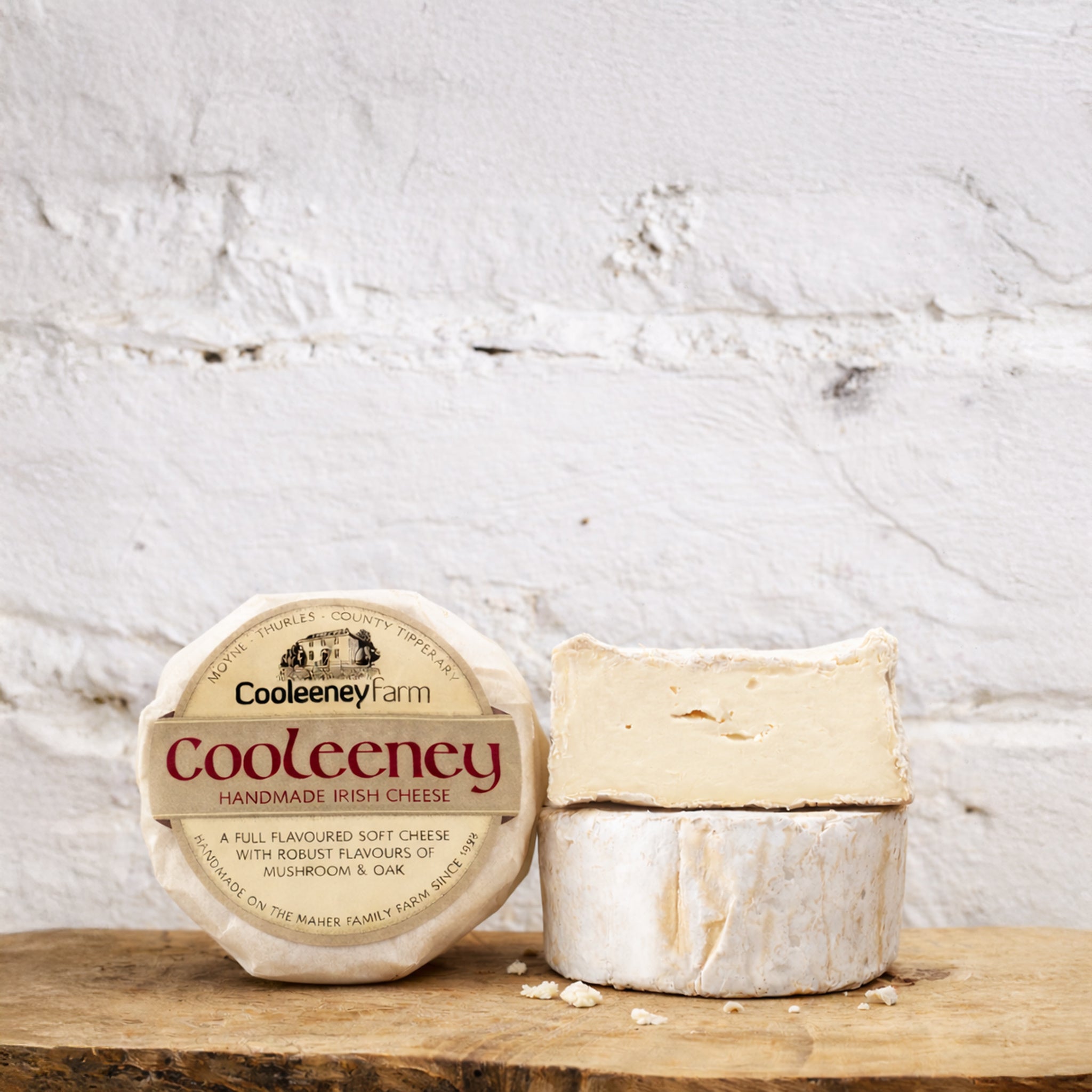 Cooleeney Farm handmade Irish cheese on a wooden board with a white textured background