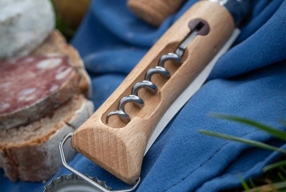 Wooden corkscrew on a blue surface with bread and salami in the background