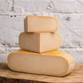 Three blocks of cheese stacked on a wooden surface with a rustic background