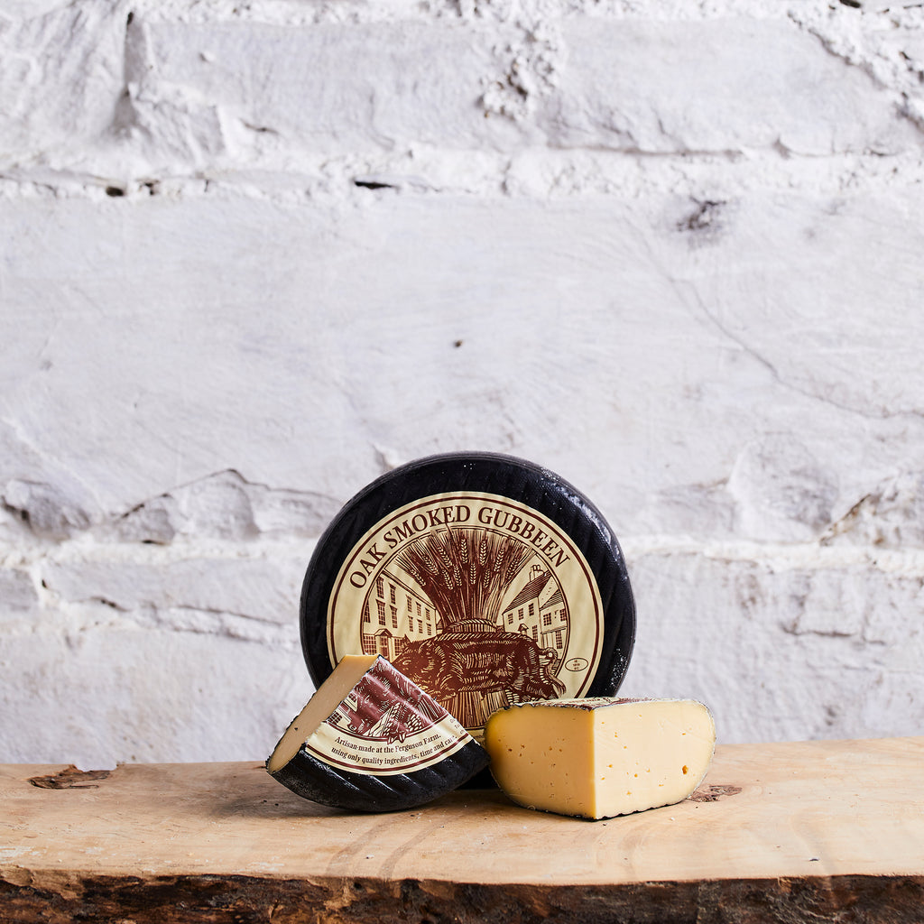 Two types of cheese with labels on a wooden surface against a marble background
