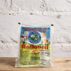 Packaged halloumi cheese with a brand label on a wooden surface and light gray background