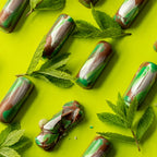 Green and brown chocolate truffles with mint leaves on a bright green background