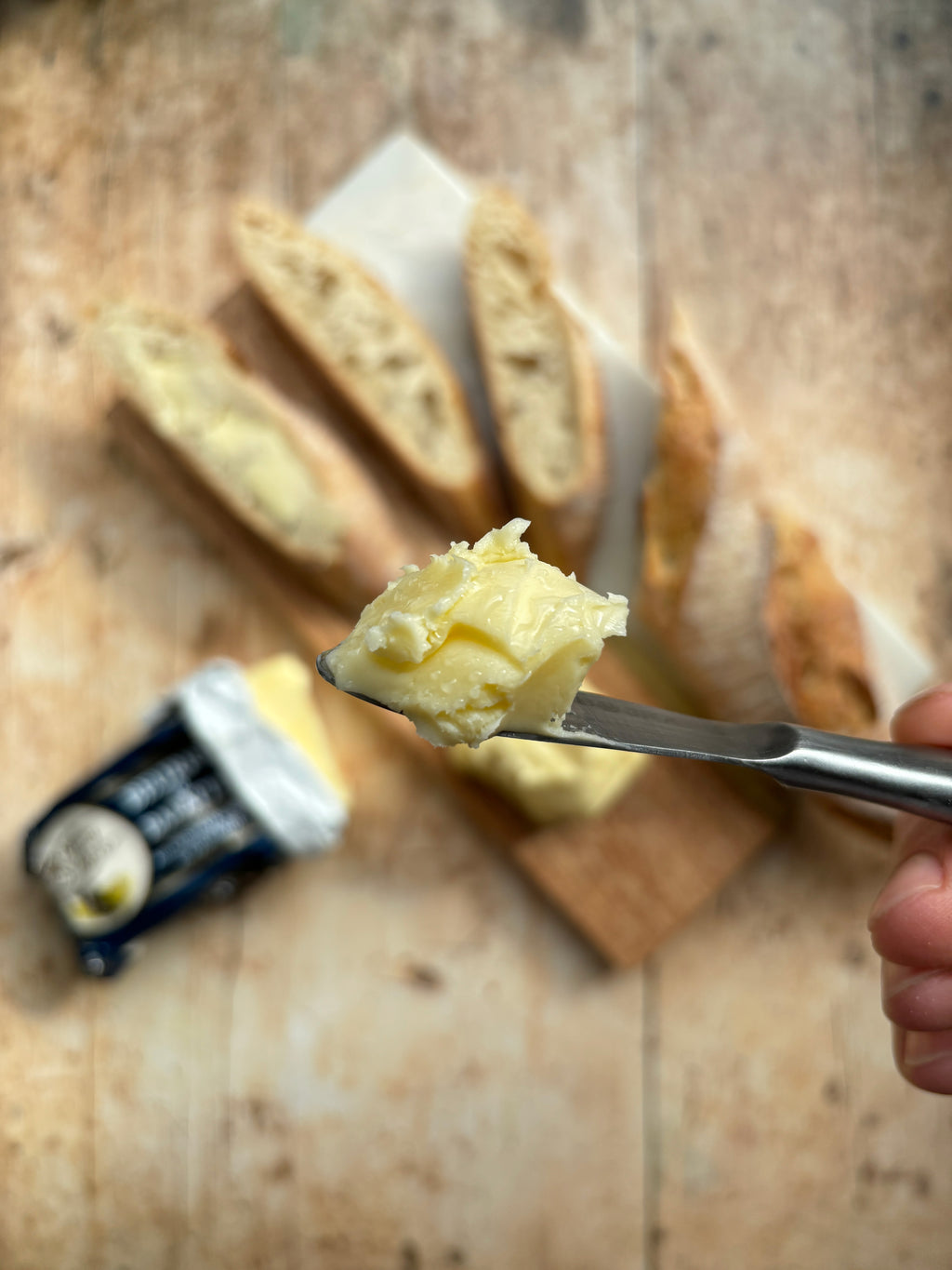 Butter on a knife with bread slices in the background