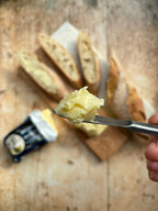Butter on a knife with bread slices in the background