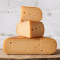 Stack of three blocks of cheese on a wooden surface with a light gray background