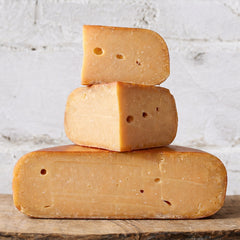 Stack of three blocks of cheese on a wooden surface with a light gray background