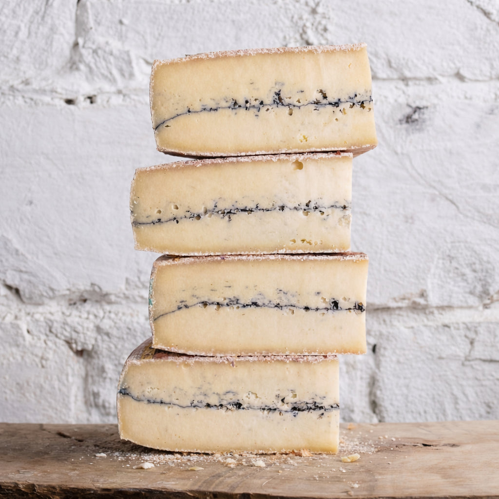 Stack of blue-streaked cheese on a wooden surface with a white textured background