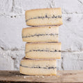 Stack of blue-streaked cheese on a wooden surface with a white textured background