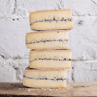 Stack of blue-streaked cheese on a wooden surface with a white textured background