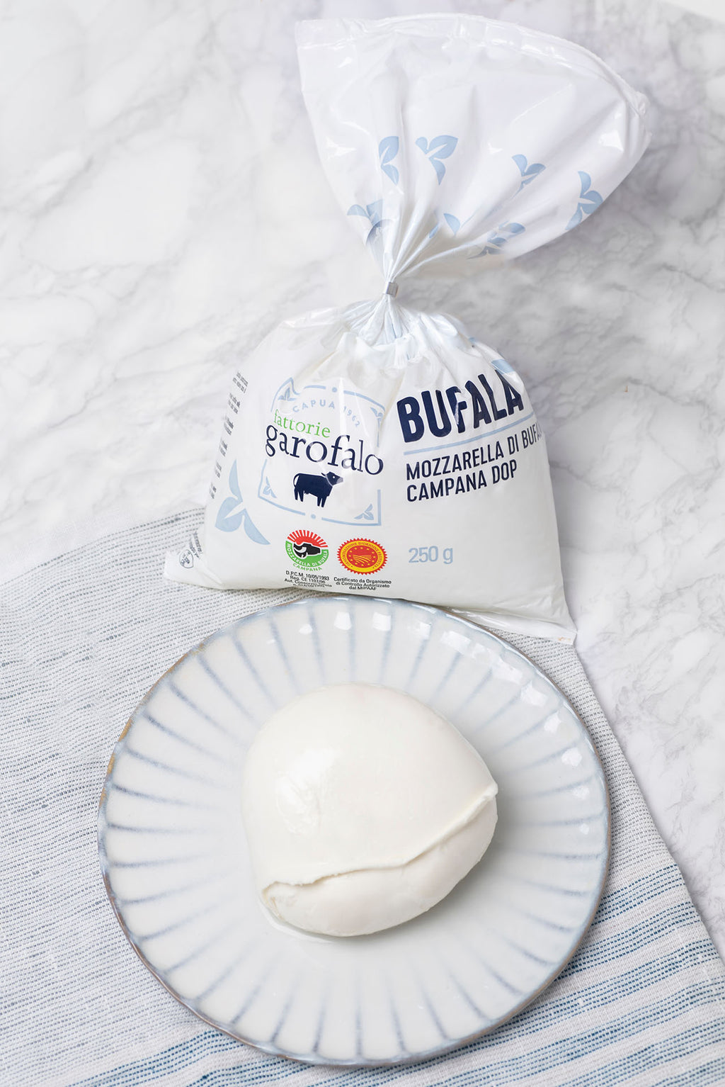 Ball of buffalo mozzarella on a plate beside its bag