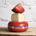 Three types of cheese stacked on a wooden surface with a rustic background