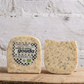 Two blocks of gouda cheese with a Sheridan's label on a wooden surface against a textured white wall.