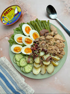 Plated salad with hard-boiled eggs, green beans, and tuna next to a can of Oster tuna.