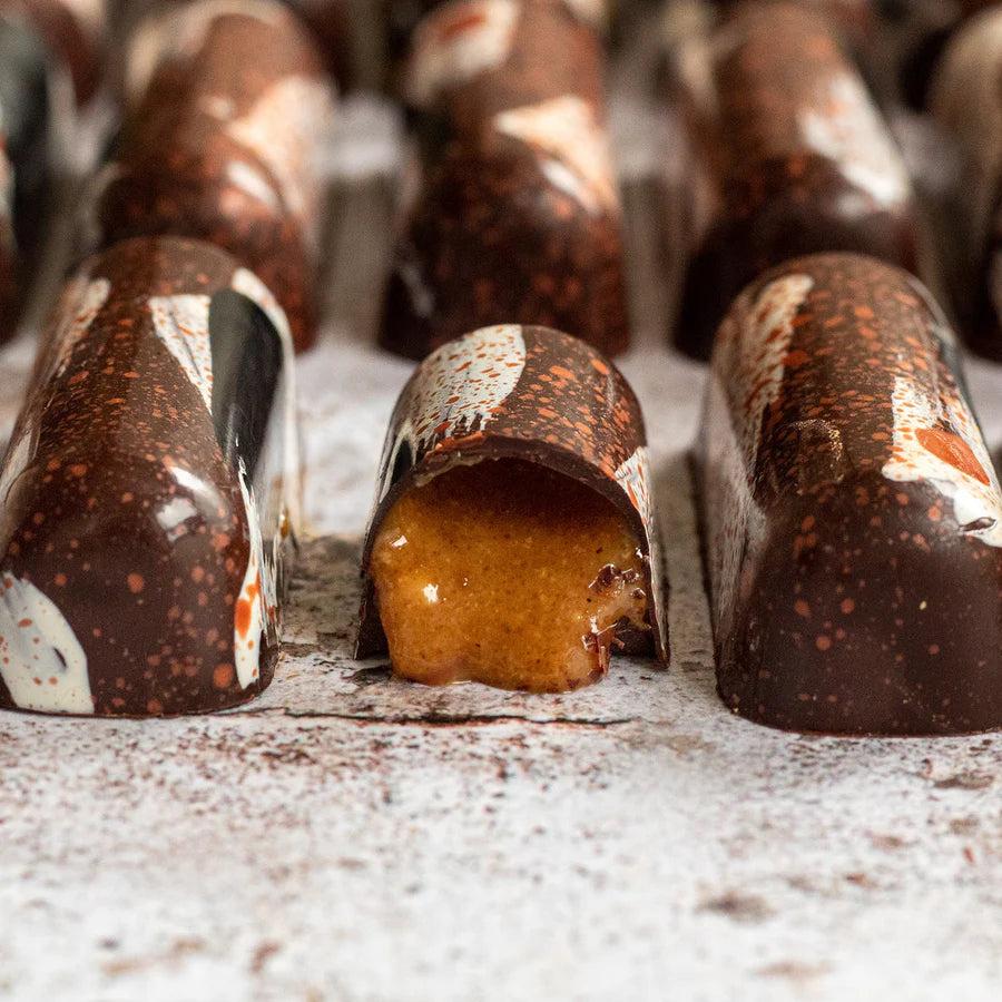 Close-up of chocolate truffles with one open showing a filling on a powdered sugar surface.