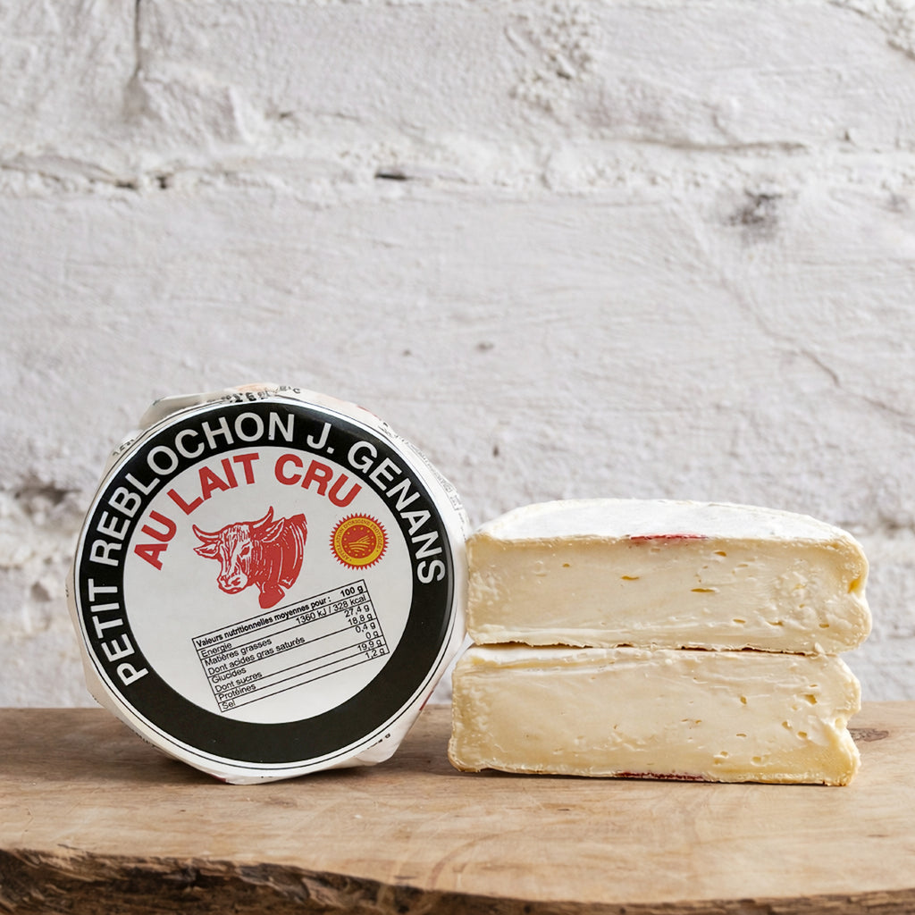 Cheese with a round label on a wooden surface against a textured white wall