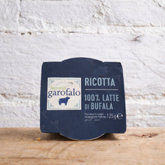 Packaged ricotta cheese with Garofalo label on a wooden surface and white textured wall background