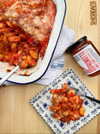 Gnocchi dish with a jar of sauce on a wooden table