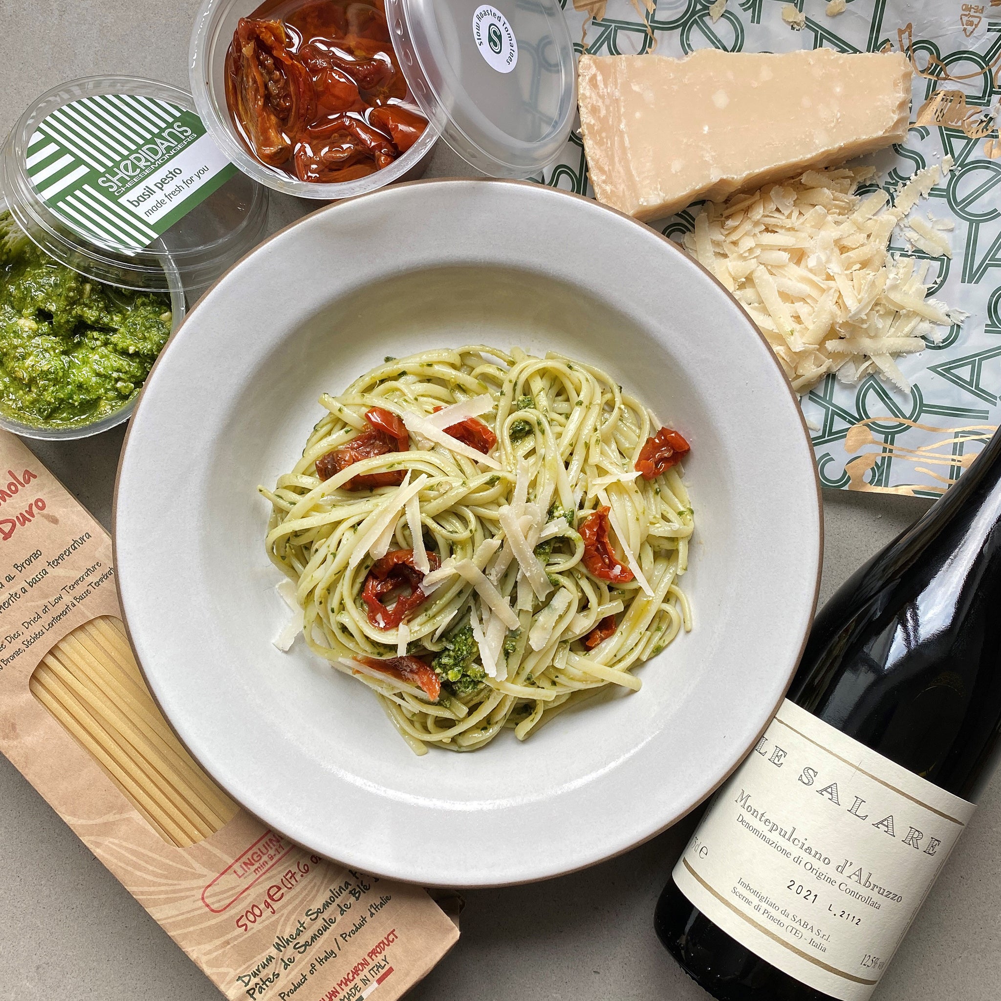 Pasta dish with ingredients and a bottle of wine on a table