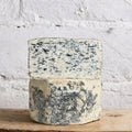 Stacked wedges of St Agur blue cheese against a white brick wall