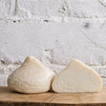 Two blocks of cheese on a wooden surface with a white brick wall background