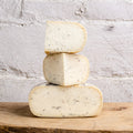 Stack of three blocks of cheese on a wooden surface with a light gray stone background