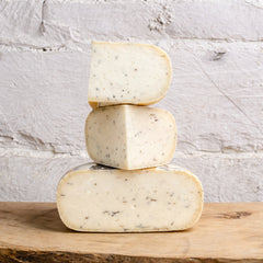 Stack of three blocks of cheese on a wooden surface with a light gray stone background