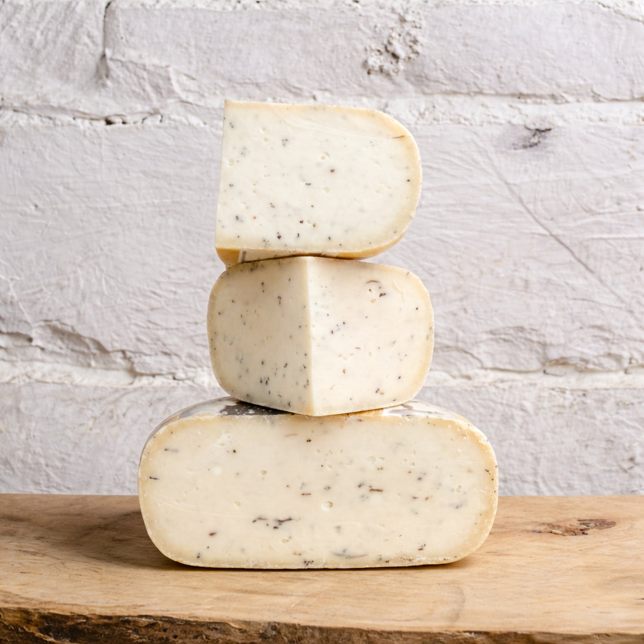 Stack of three blocks of cheese on a wooden surface with a light gray stone background