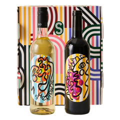 Two wine bottles with colorful labels in front of a patterned box.