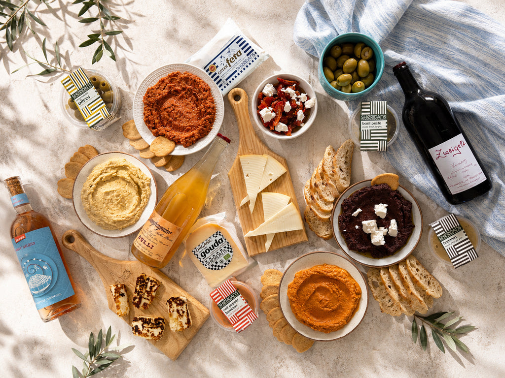 Assorted food items including dips, bread, and wine on a textured surface with a bottle of wine.