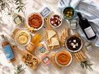 Assorted food items including dips, bread, and wine on a textured surface with a bottle of wine.