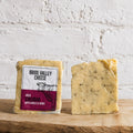 Bride Valley Cheese Irish Cheddar with Garlic & Herbs on a wooden surface with a white brick wall background.