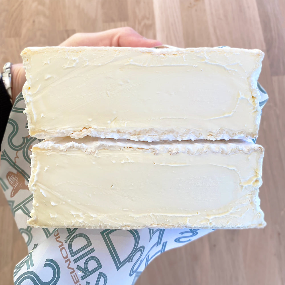 Two slices of white cheese held by a hand on a wooden surface