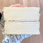 Two slices of white cheese held by a hand on a wooden surface