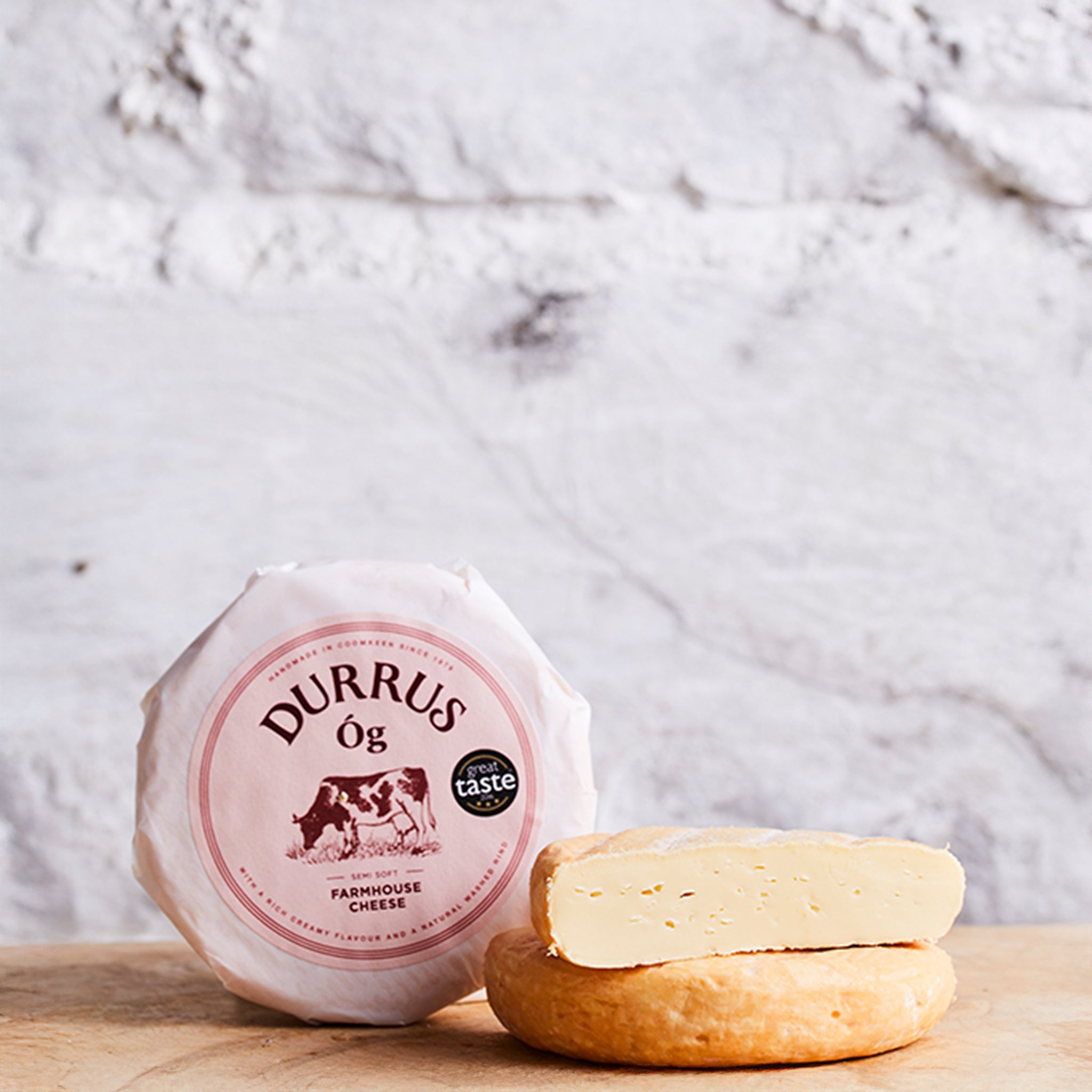 Durrus Og cheese with packaging on a wooden surface against a marble background