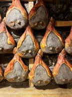 Cured ham legs stacked on a wooden pallet