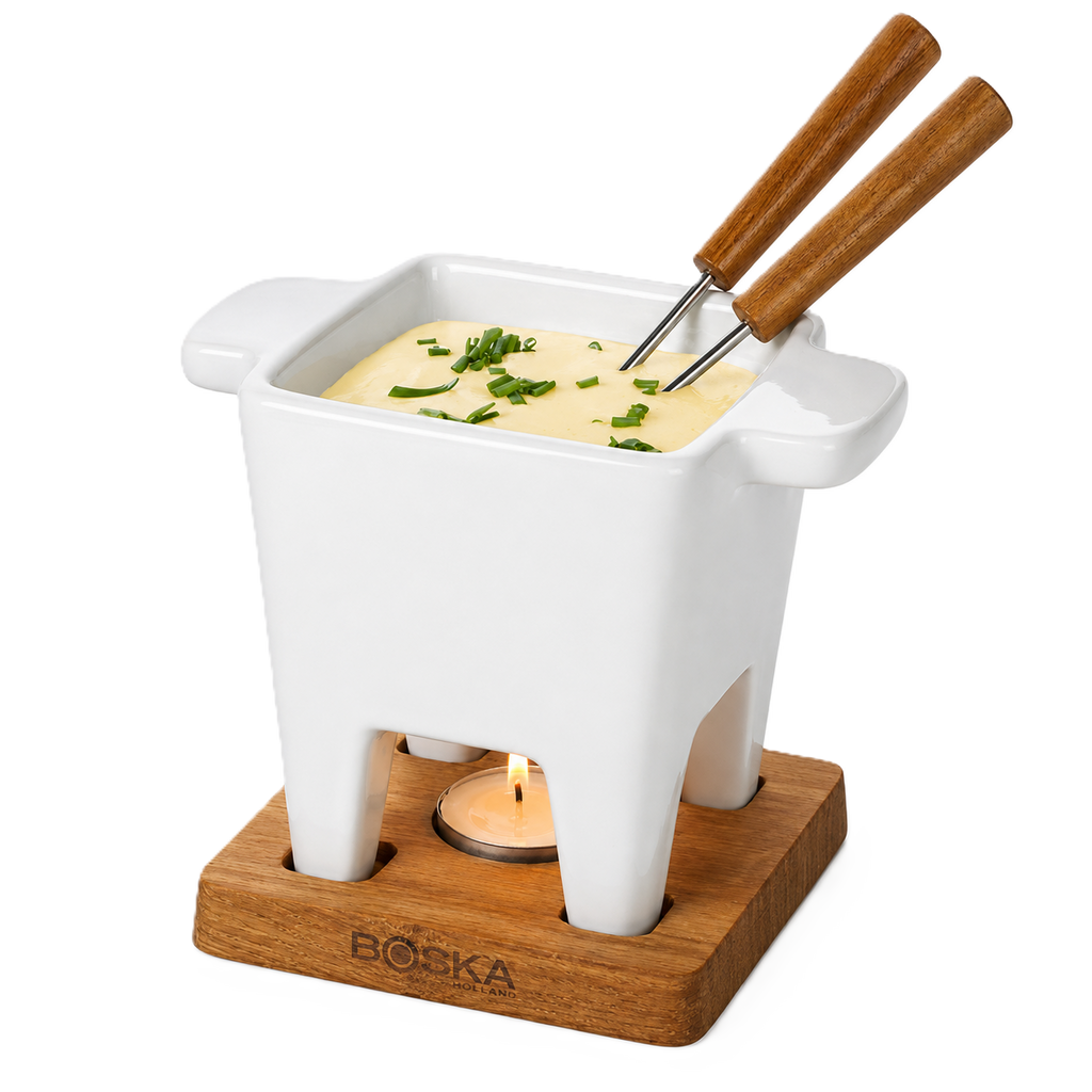 White fondue pot with wooden handles on a wooden base, filled with cheese fondue and garnished with herbs.