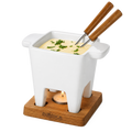 White fondue pot with wooden handles on a wooden base, filled with cheese fondue and garnished with herbs.