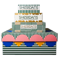 Three stacked boxes of Sheridan's Cheeseemongers with a colorful retro design featuring green and white stripes, pink, blue, and yellow scalloped patterns, and gold accents.